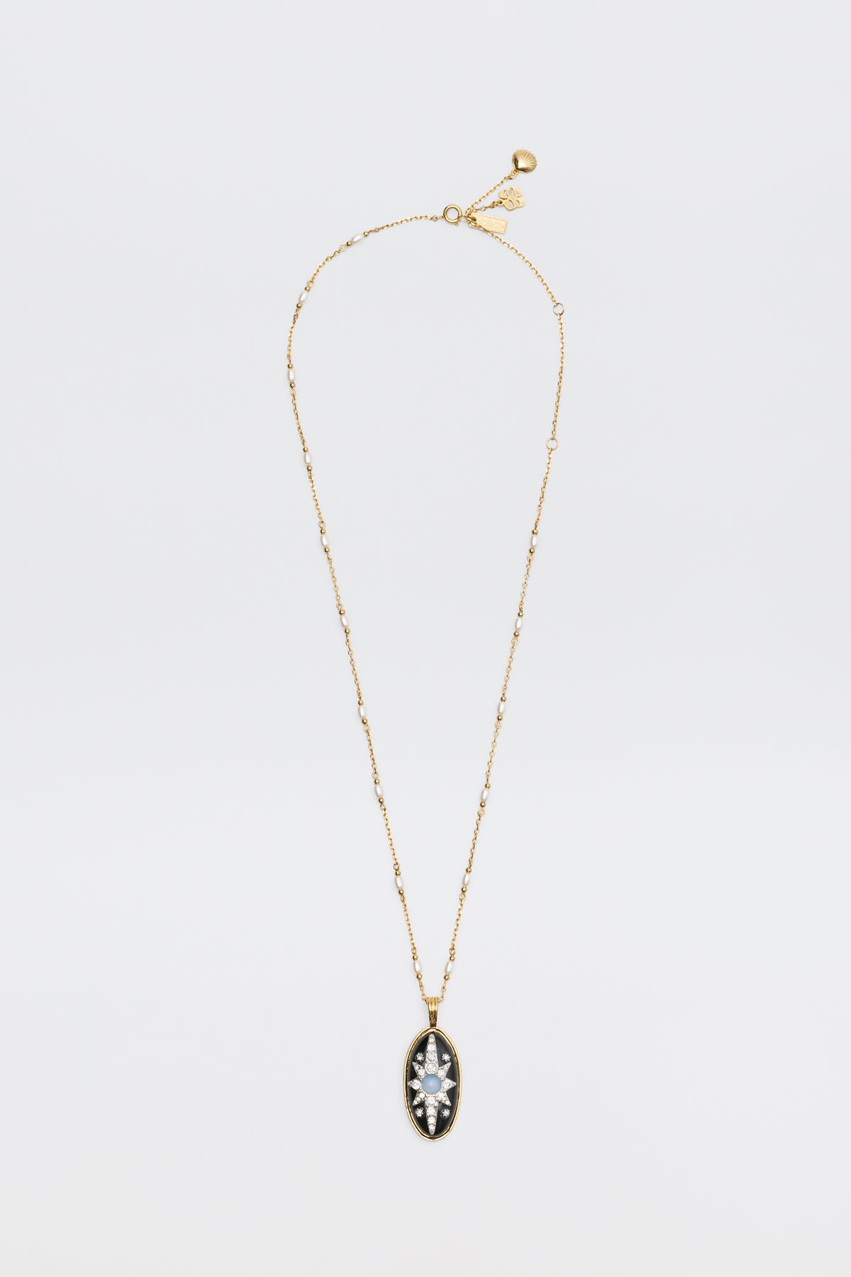 Introducing the Andi - Black necklace: a delicate gold chain adorned with small beads and an oval pendant, featuring a clear marquise-cut gemstone set in a striking black and gold frame, beautifully displayed on a white background.
