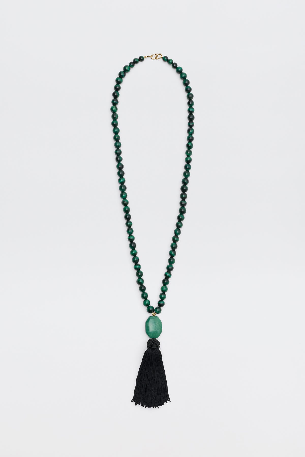 Cally - Green is a necklace featuring small round green beads, a large oval green bead at the center, and a long black tassel hanging at the bottom, displayed on a white background.