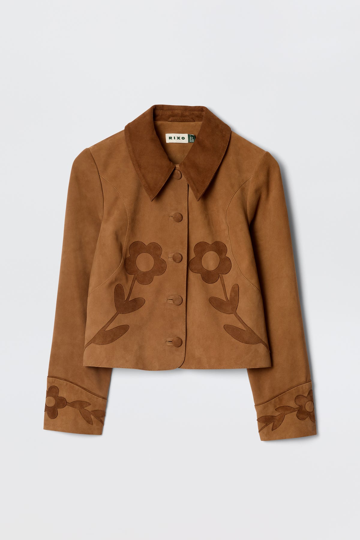 The Dionne - Retro Daisy is a brown suede jacket featuring a wide collar, button-up front, and decorative dark brown floral patterns on the front and cuffs, inspired by classic vintage souvenir jacket styles.