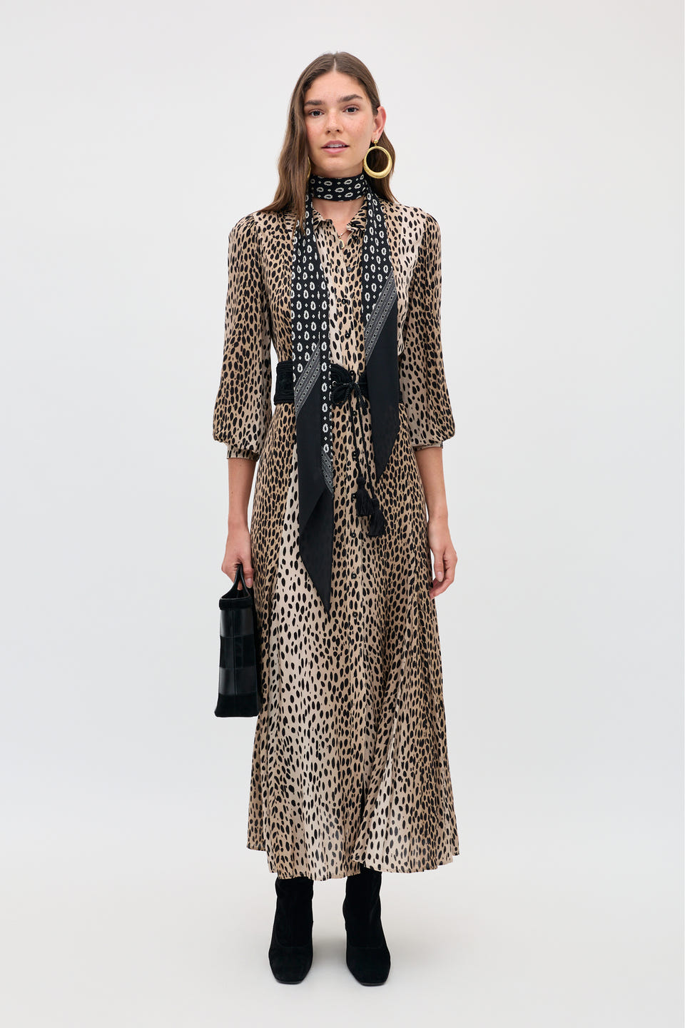 A petite woman wears a Maddison - Antelope Spot Black midi shirt dress, a black patterned scarf, and black ankle boots while holding a small black handbag.