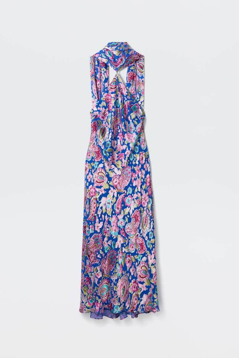 The Hayley - Cara Floral Devore Blue is a sleeveless, long dress featuring a vibrant floral paisley print in blue, pink, and purple tones. The back is designed with a shawl collar and an upper back cut-out detail.