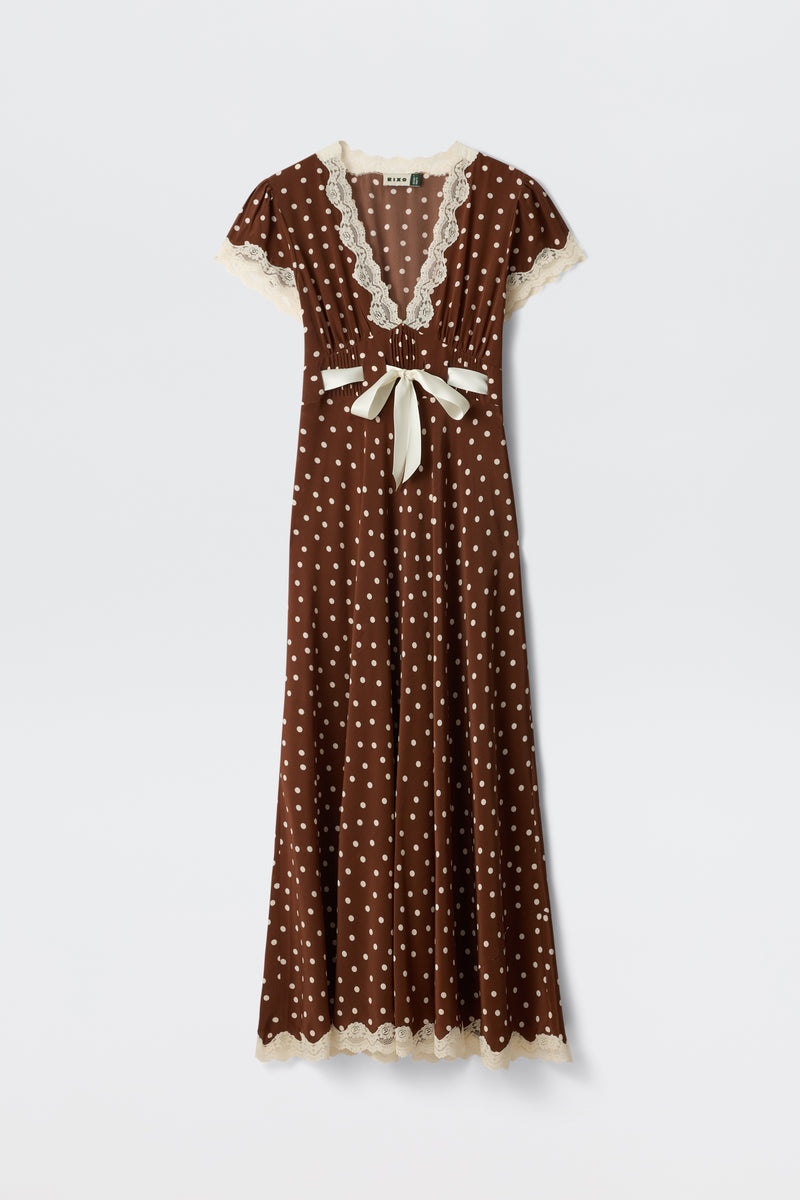 Marlice - Layla Dot Brown is a brown, floor-length dress featuring white polka dots, cream lace trim on the sleeves, neckline, and hem, a deep V-neckline, short sleeves, and a cream ribbon bow accentuating the waist.