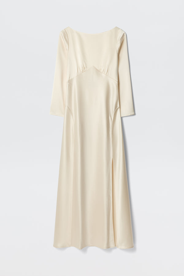 The Devina - Pearl is a long ivory satin dress with three-quarter sleeves, a fitted bodice featuring subtle seam details, and a slight side slit. Its minimalist, elegant design is shown against a plain white background.
