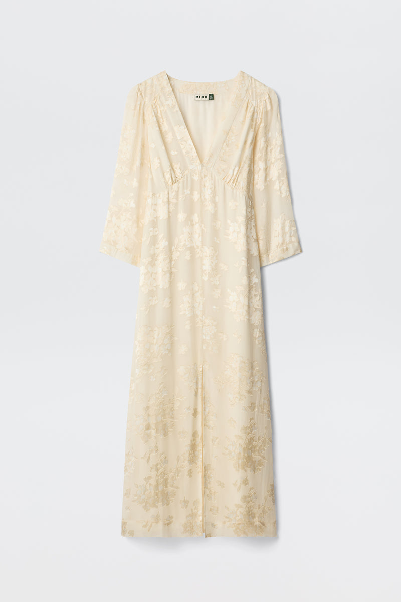 The Dahlia - Bouquet Devore Cream is a long, cream-colored dress with a V-neckline, three-quarter sleeves, and a delicate floral pattern, shown against a plain white background.