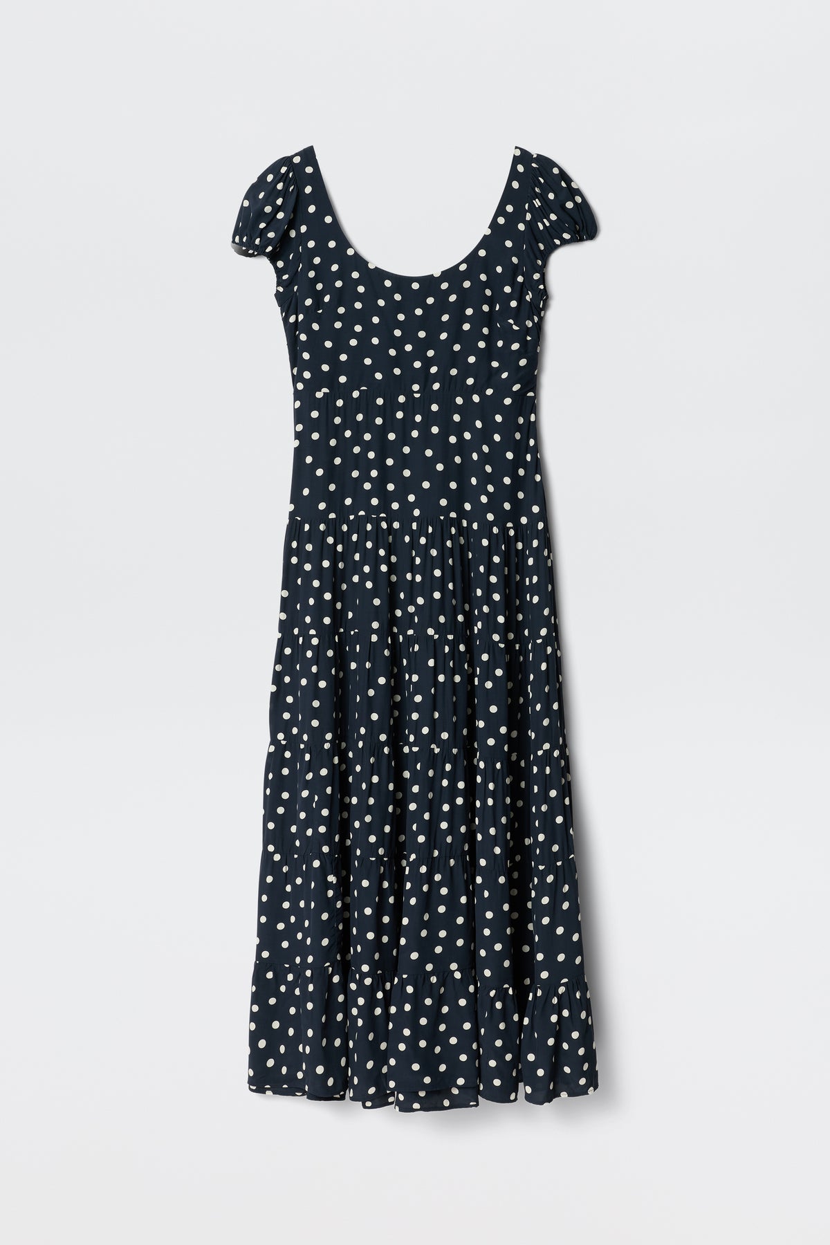 The Remi - Bohemia Spot Deep Navy dress features a scoop neck, white polka dots, short sleeves, and an ankle-length tiered skirt—ideal for summer and shown on a plain white background.