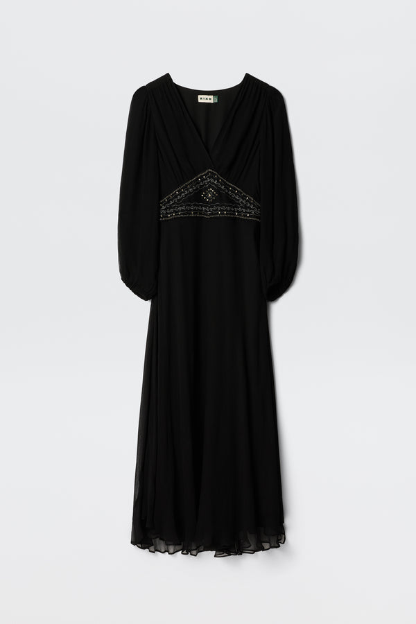 The Kaesha - Diana Embellishment Black dress features a V-neck, three-quarter sleeves, beaded detail under the bust, sheer hem and sleeves, and a softly draped flowing skirt. Shown hanging against a plain background.