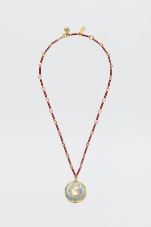 Ari - Astro Pisces: A gold and red beaded necklace featuring a circular statement disc pendant with a colorful rooster design on a white background, displayed against a white surface.