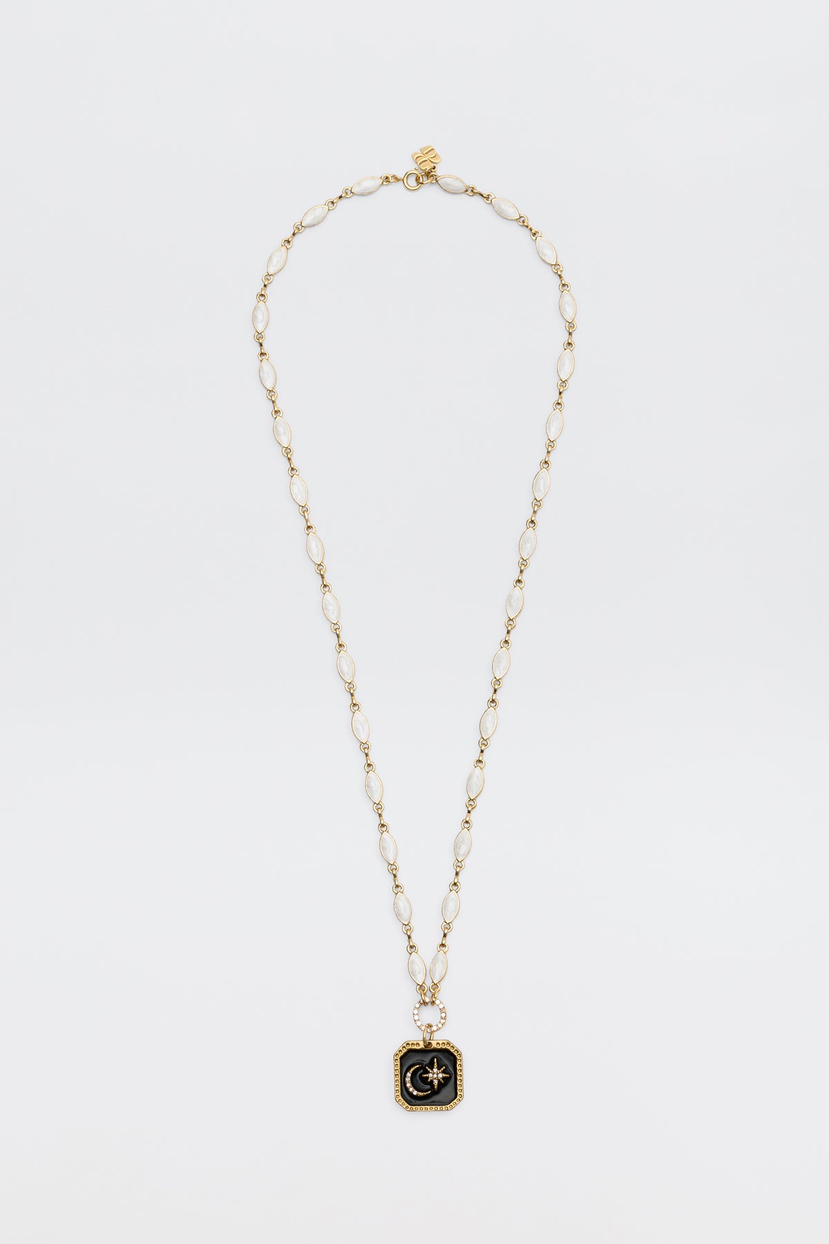 A gold chain necklace named “Kathryn - Pearl,” featuring oval links and a square black pendant adorned with a gold starburst design at the center, displayed on a white background.