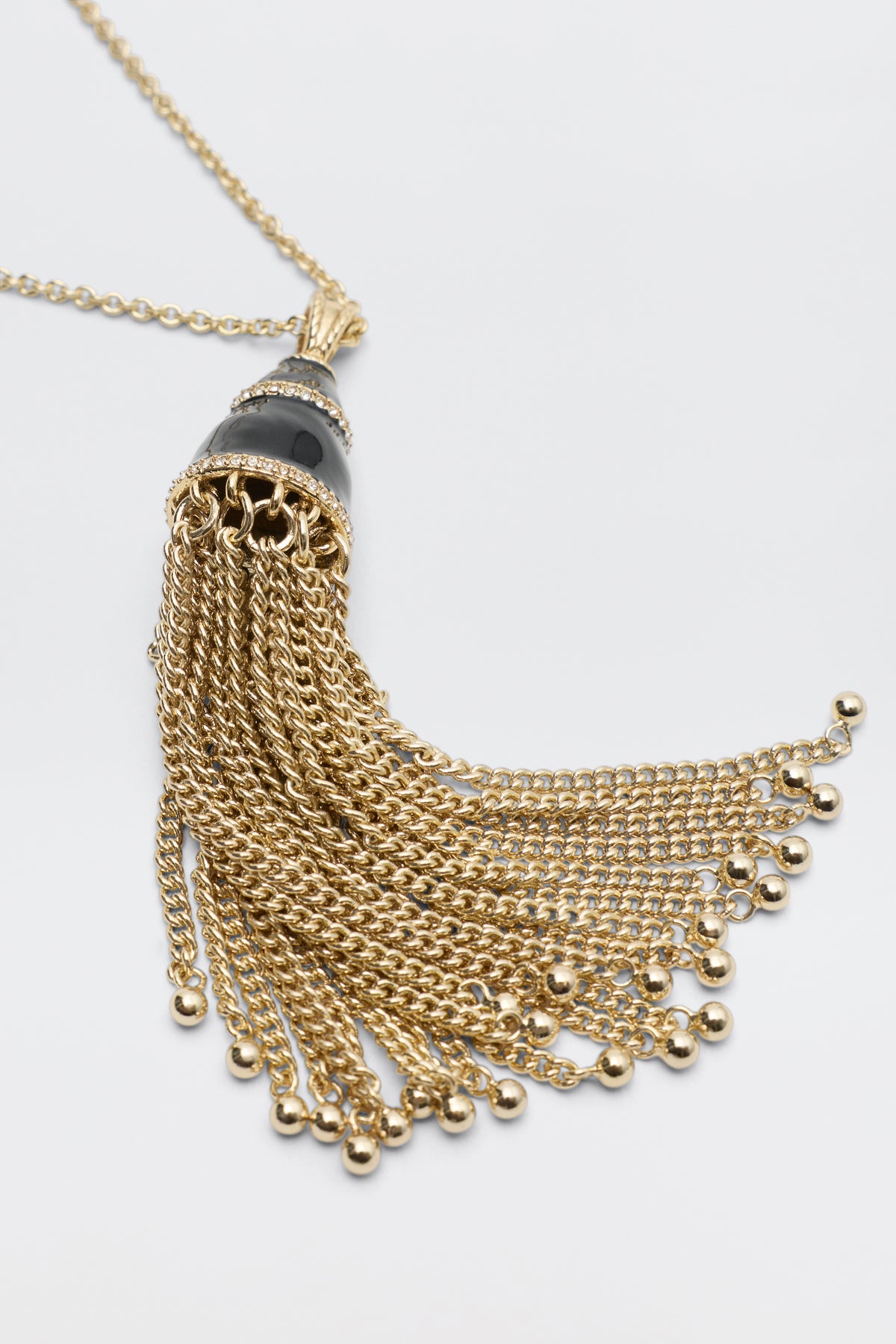 Lizbeth - Gold tassel pendant necklace featuring a black stone cap and small bead accents at the ends of the chains.