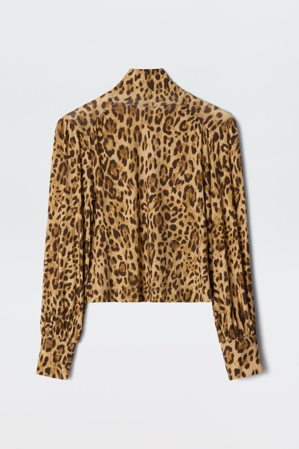 The Suki - Mila Leopard Brown is a long-sleeve, button-down blouse featuring a brown and black leopard print, shown flat with the back visible—ideal for layering over turtlenecks or jerseys for extra warmth and style.