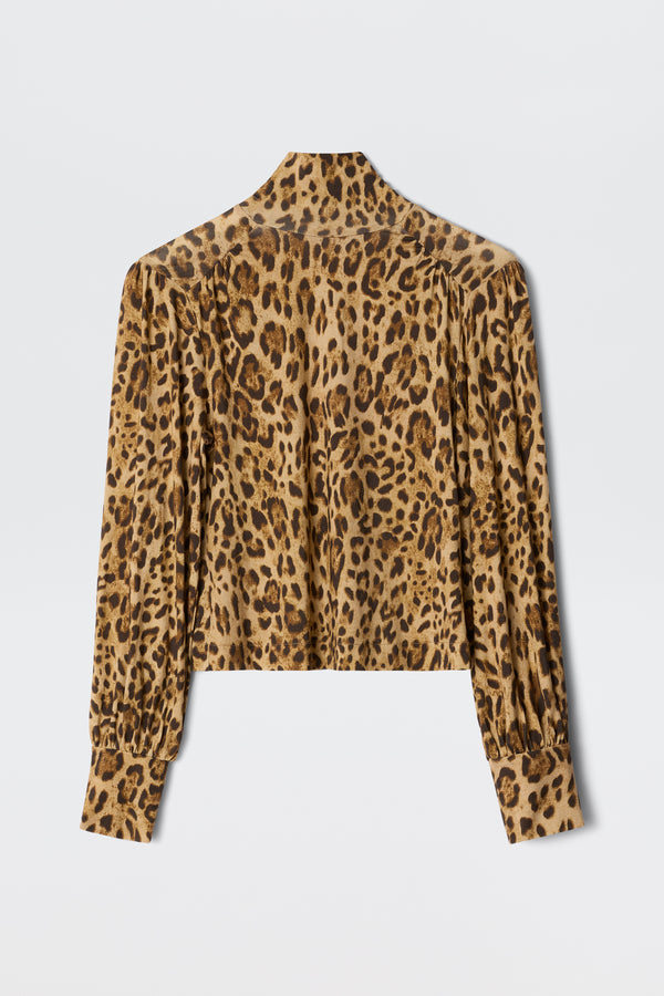 The Suki - Mila Leopard Brown is a long-sleeve, button-down blouse featuring a brown and black leopard print, shown flat with the back visible—ideal for layering over turtlenecks or jerseys for extra warmth and style.