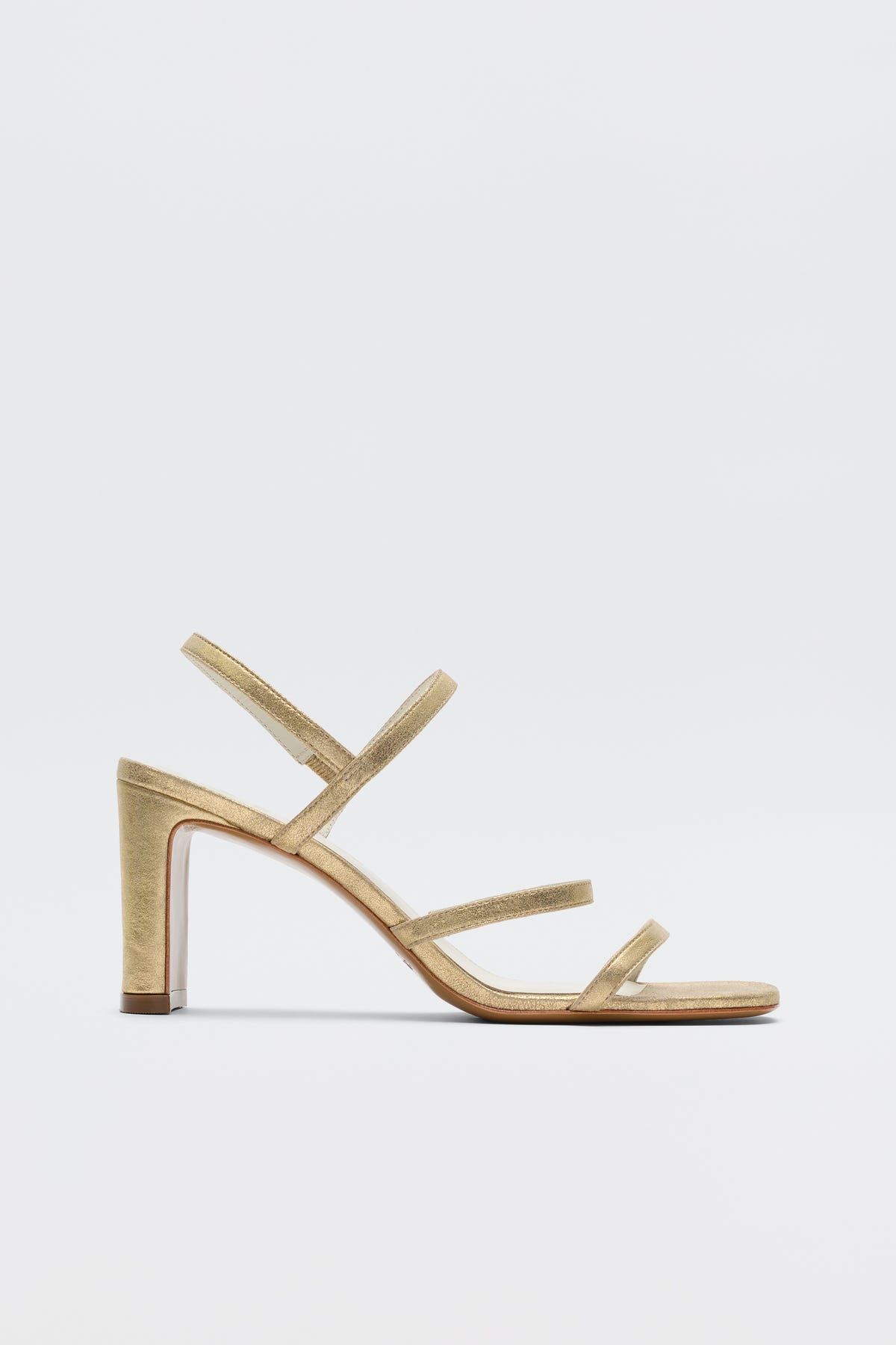 The Ciervo - Gold is a stylish strappy sandal with three slim front straps, an ankle strap, a comfy mid-height block heel, and an open toe—ideal for RIXO occasion wear. Photographed on a plain white background.