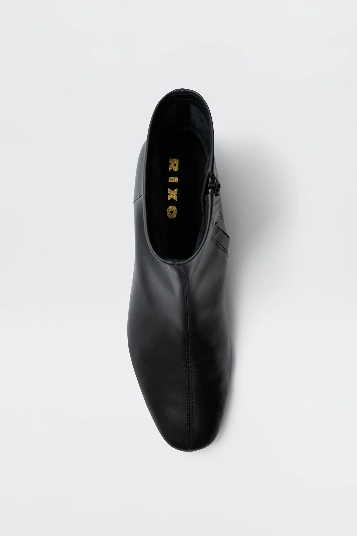 Top view of the Rey - Black Leather ankle boot, featuring a rounded toe and visible gold RIXO branding on the insole, set against a plain white background.