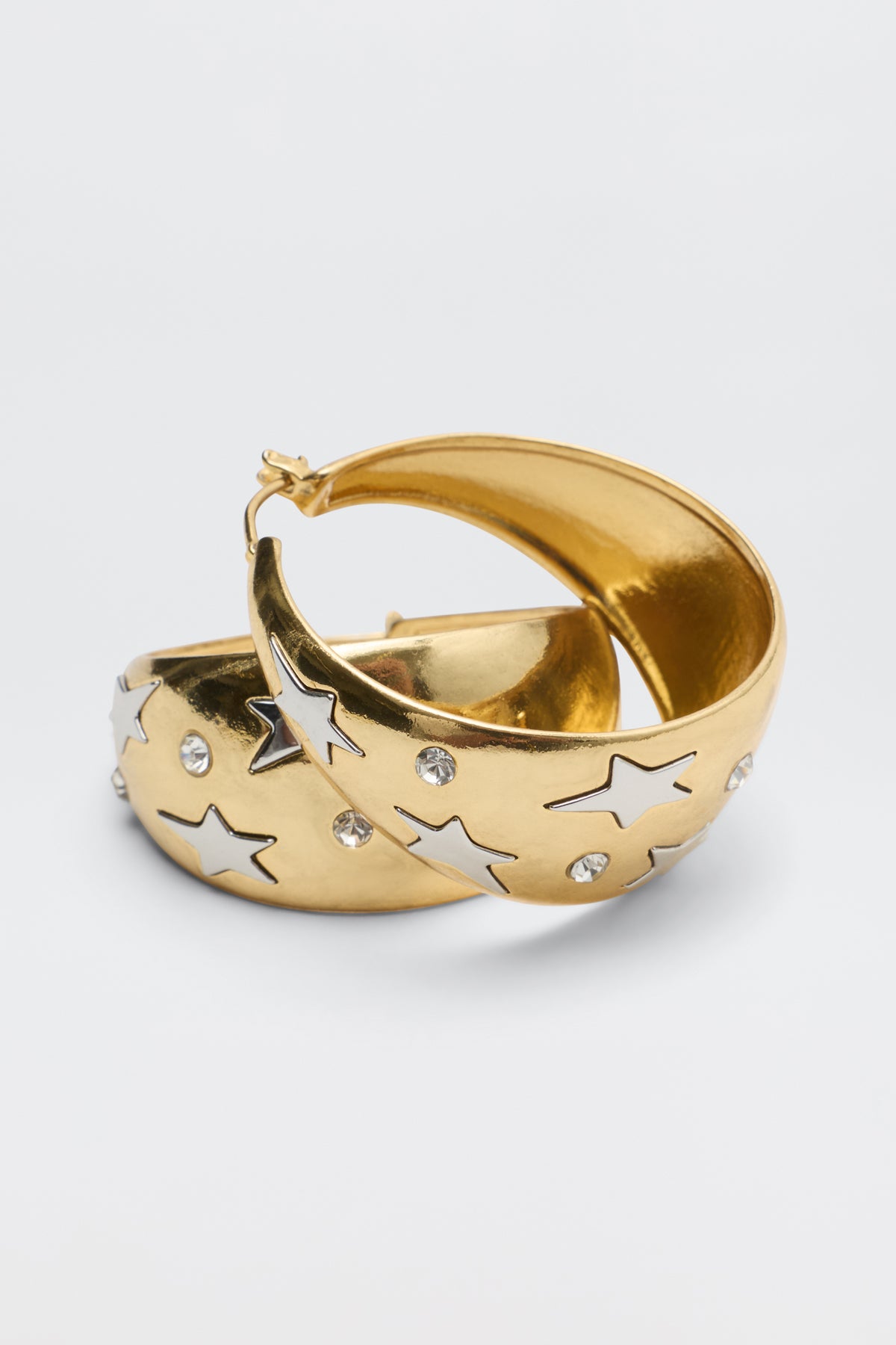 Sergio - Gold hoop earrings featuring silver star-shaped inlays and embedded clear crystals.