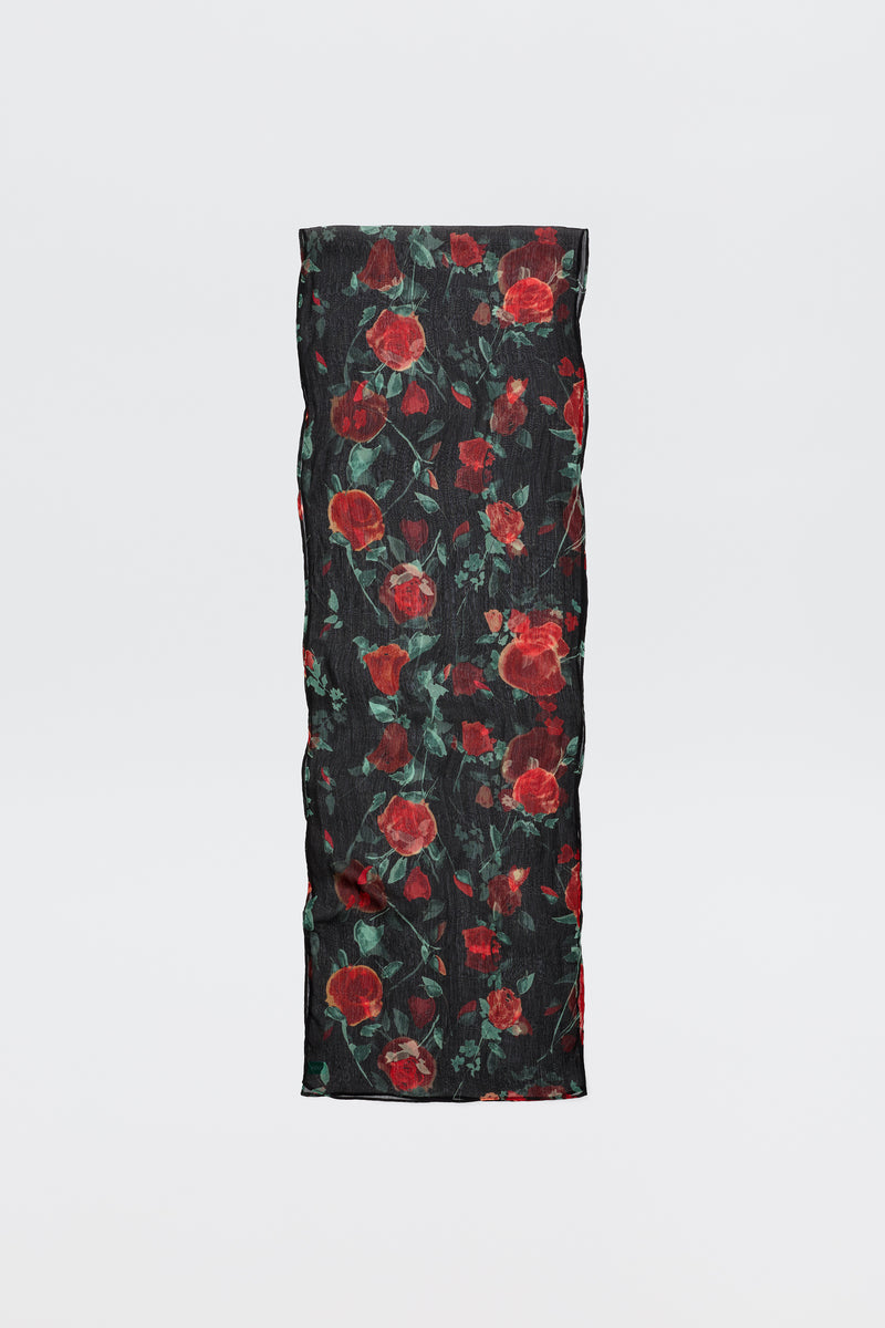 The Julien - Claudia Rose Black is a long, rectangular black scarf featuring red rose patterns with green leaves, displayed against a plain light background.