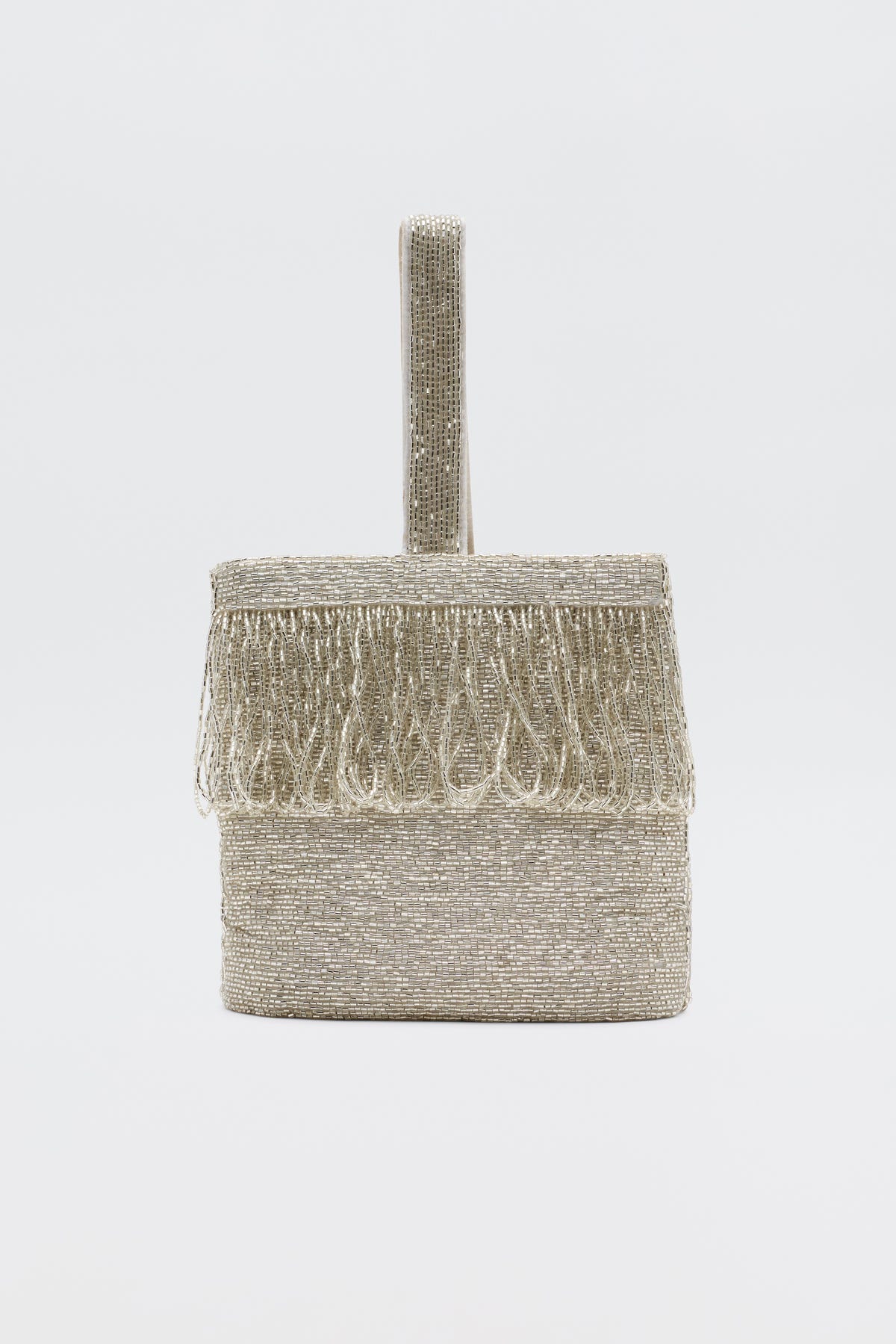 The Zenni - Beaded Silver clutch, a small box-shaped silver bag with a beaded texture, fringe on the top edge, and a single rounded handle, is shown as an elegant occasion accessory against a plain white background.