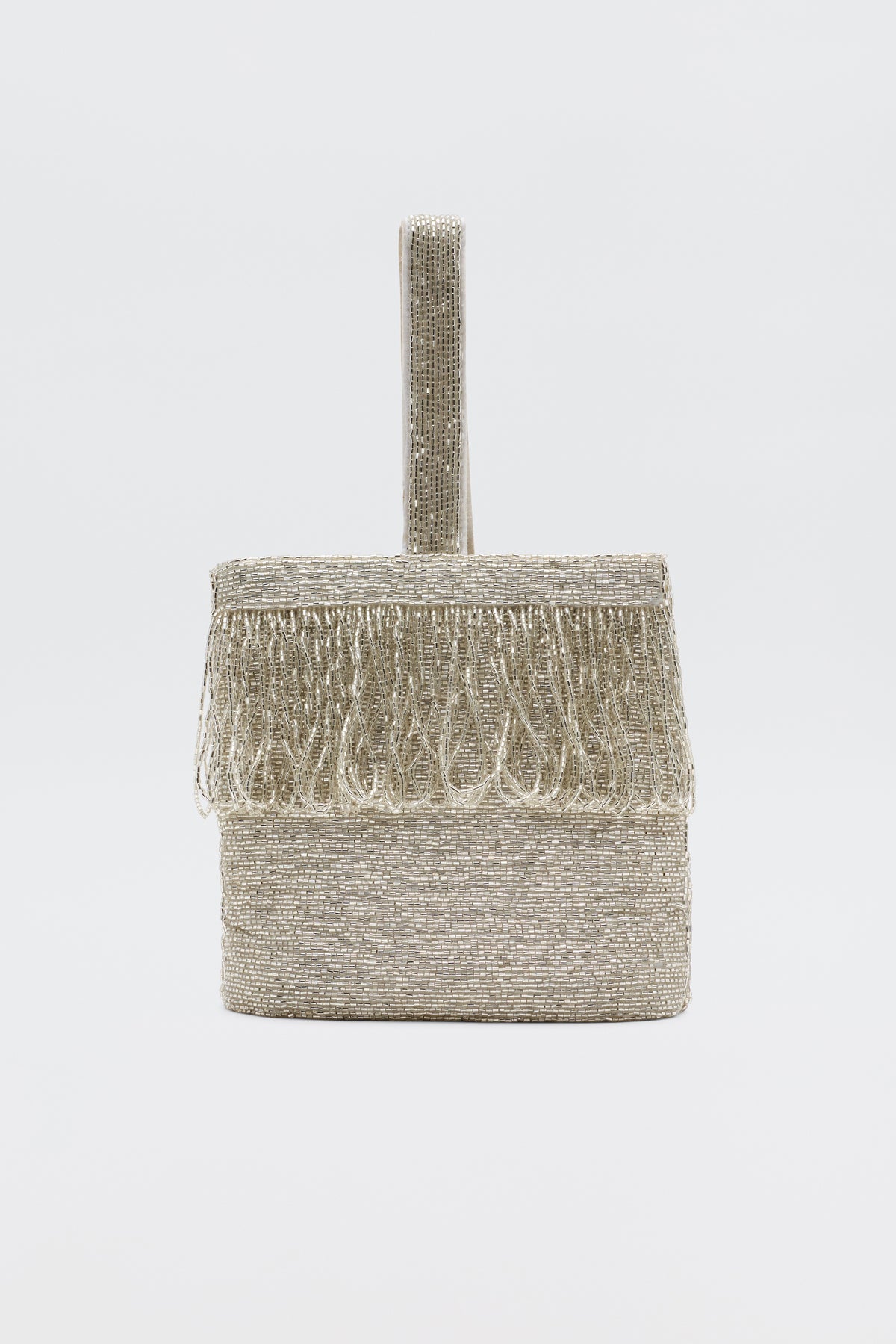The Zenni - Beaded Silver clutch, a small box-shaped silver bag with a beaded texture, fringe on the top edge, and a single rounded handle, is shown as an elegant occasion accessory against a plain white background.