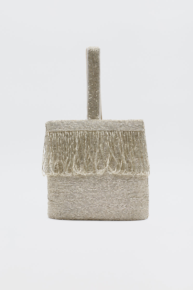The Zenni - Beaded Silver clutch, a small box-shaped silver bag with a beaded texture, fringe on the top edge, and a single rounded handle, is shown as an elegant occasion accessory against a plain white background.