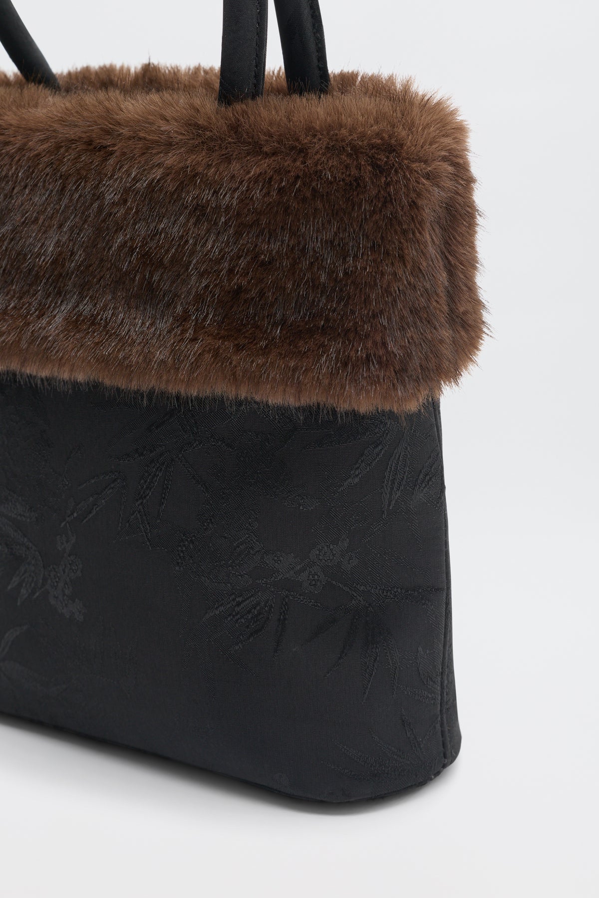 Gabbie - Black handbag with a brown faux fur trim at the top and subtle floral pattern.