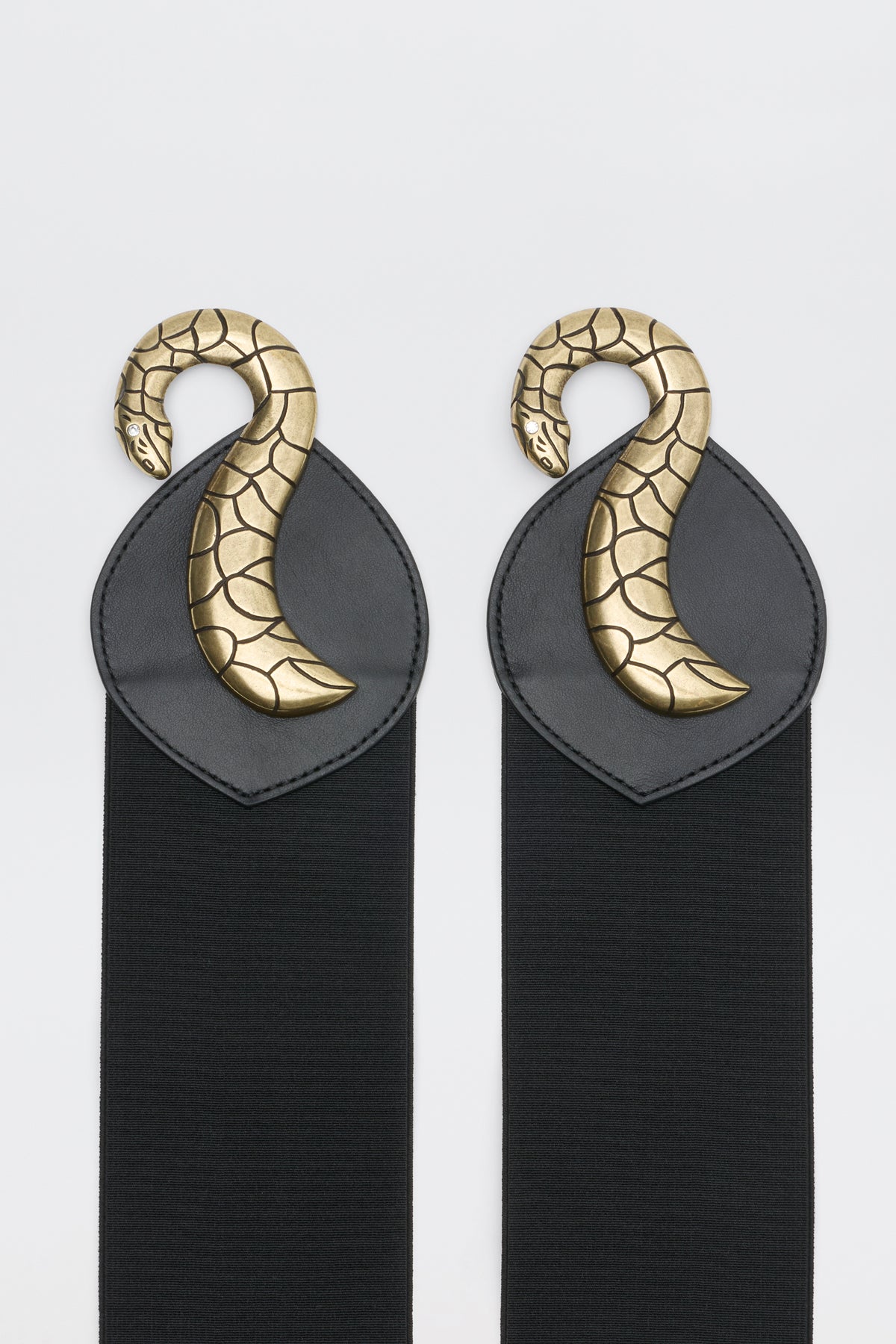 Milena - Black features two black elastic straps, each finished with a black leather patch topped by a curved, gold-tone metal snake ornament.