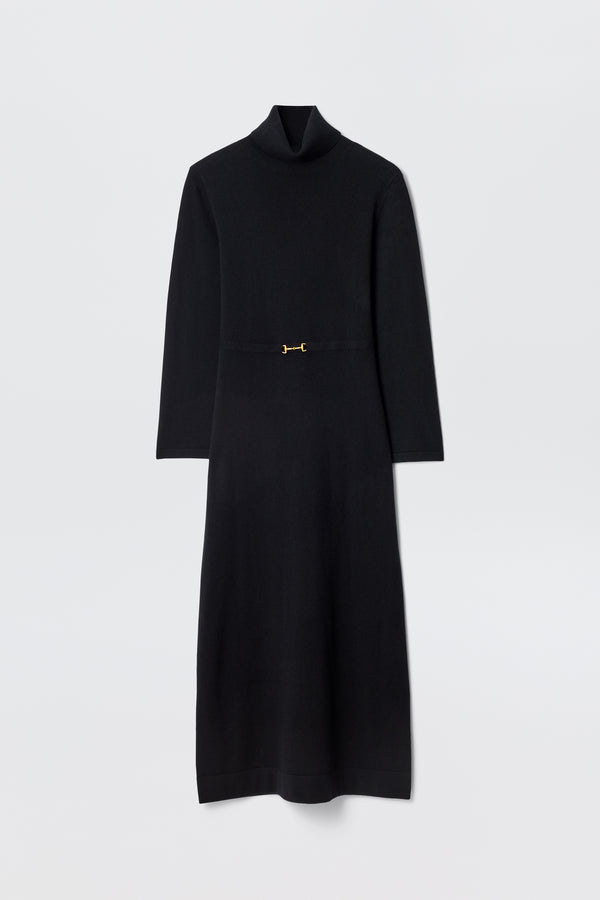 The Elliette - Black is a long-sleeved, minimalist black midi dress with a turtleneck, fitted waist, and a small gold clasp at the center, shown flat against a plain white background.