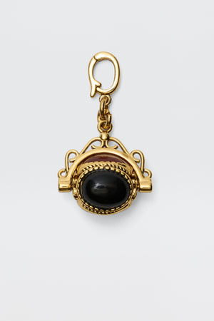 Sariah - Gold is an 18-karat gold-plated pendant featuring a large oval semi-precious stone in an intricate frame, hanging from a decorative clasp and radiating vintage charm against a plain white background.