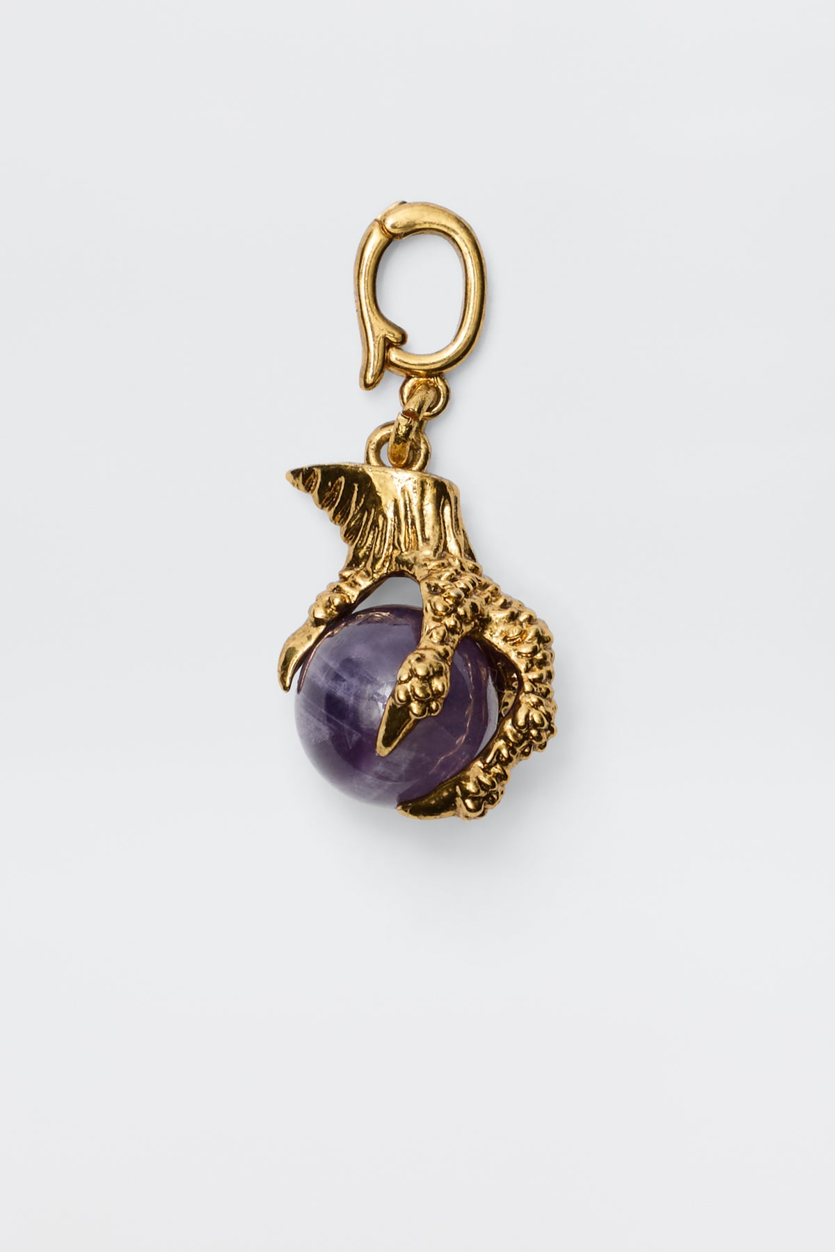 The Ianna - Gold charm features a gold-plated bird's claw gripping an Amethyst gemstone, complete with a top loop for easy attachment—ideal for vintage-inspired jewelry lovers. Photographed on a plain white background.