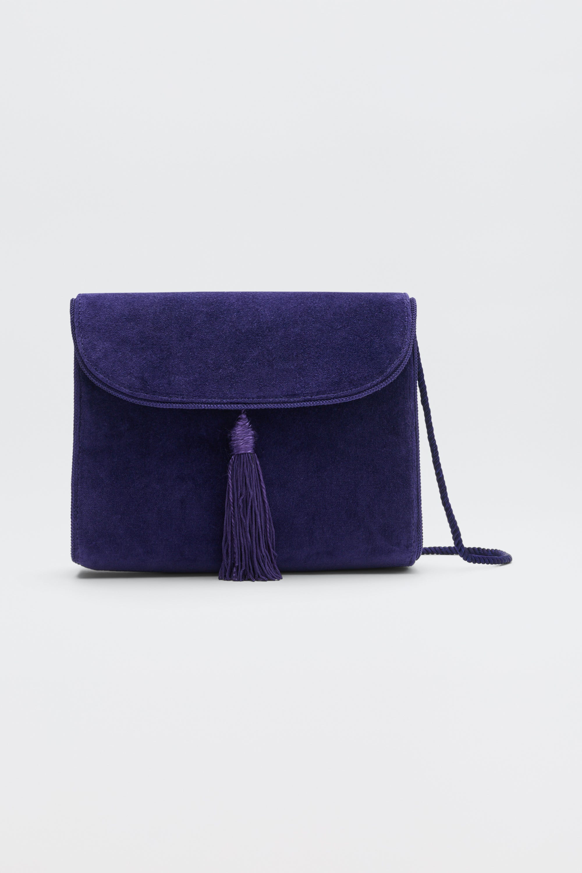 Jeany - Purple suede shoulder bag featuring a fold-over flap, a central tassel, and a thin strap.