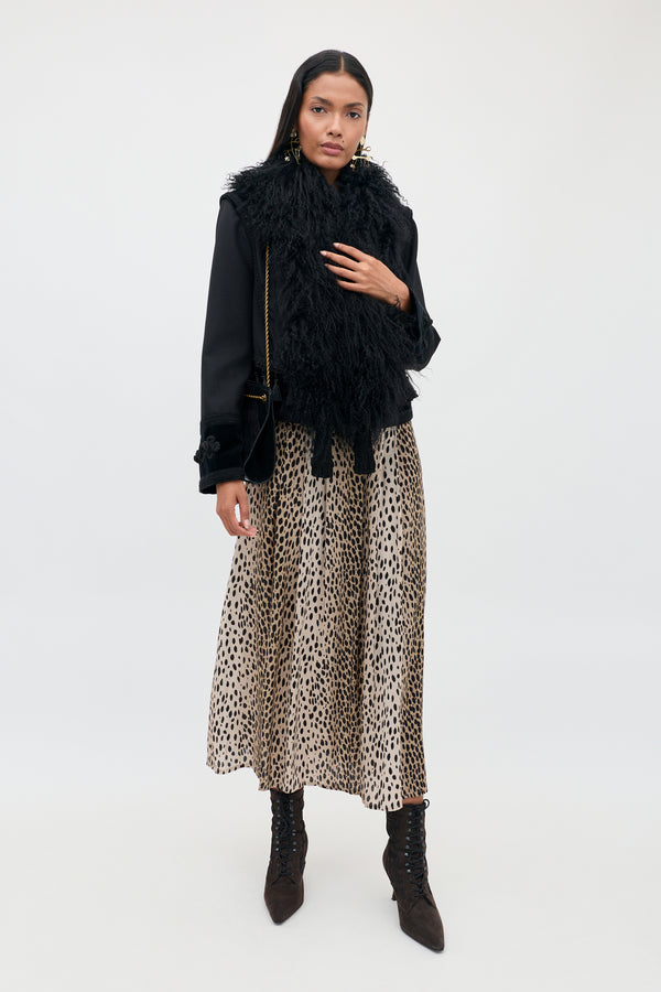 A person wearing a Kove - Black jacket with a shaggy fur-style collar, a tan midi skirt with a black animal-print pattern, and dark lace-up ankle boots.