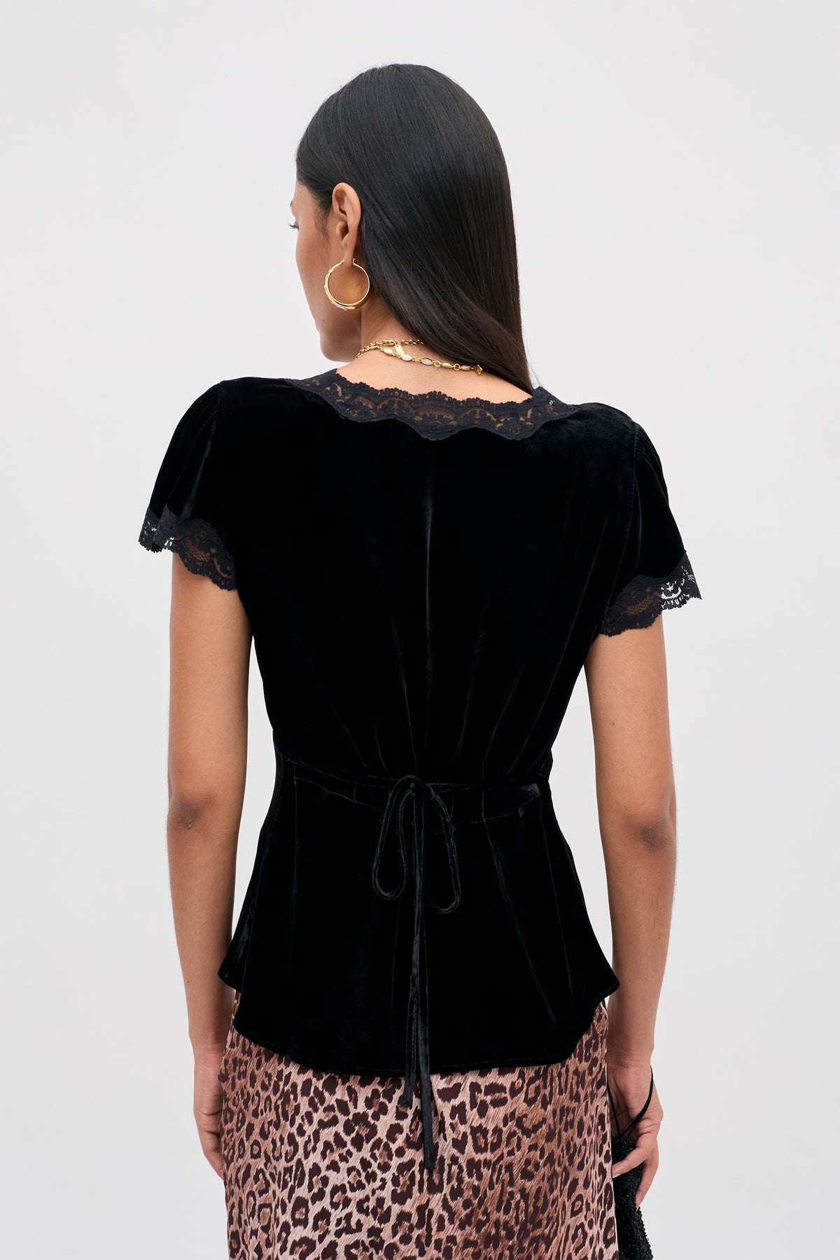Back view of the Karia - Black Velvet top featuring short sleeves, a lace-trimmed neckline, and a tie detail at the waist.