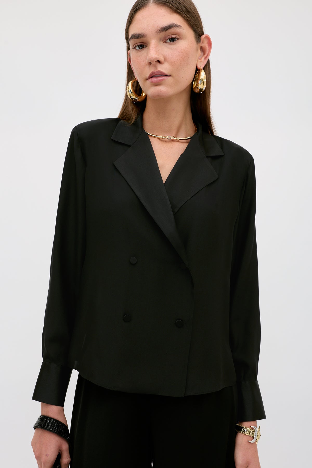 A woman wears the Lorraine - Black, a double-breasted blazer with a notched lapel and large gold hoop earrings.