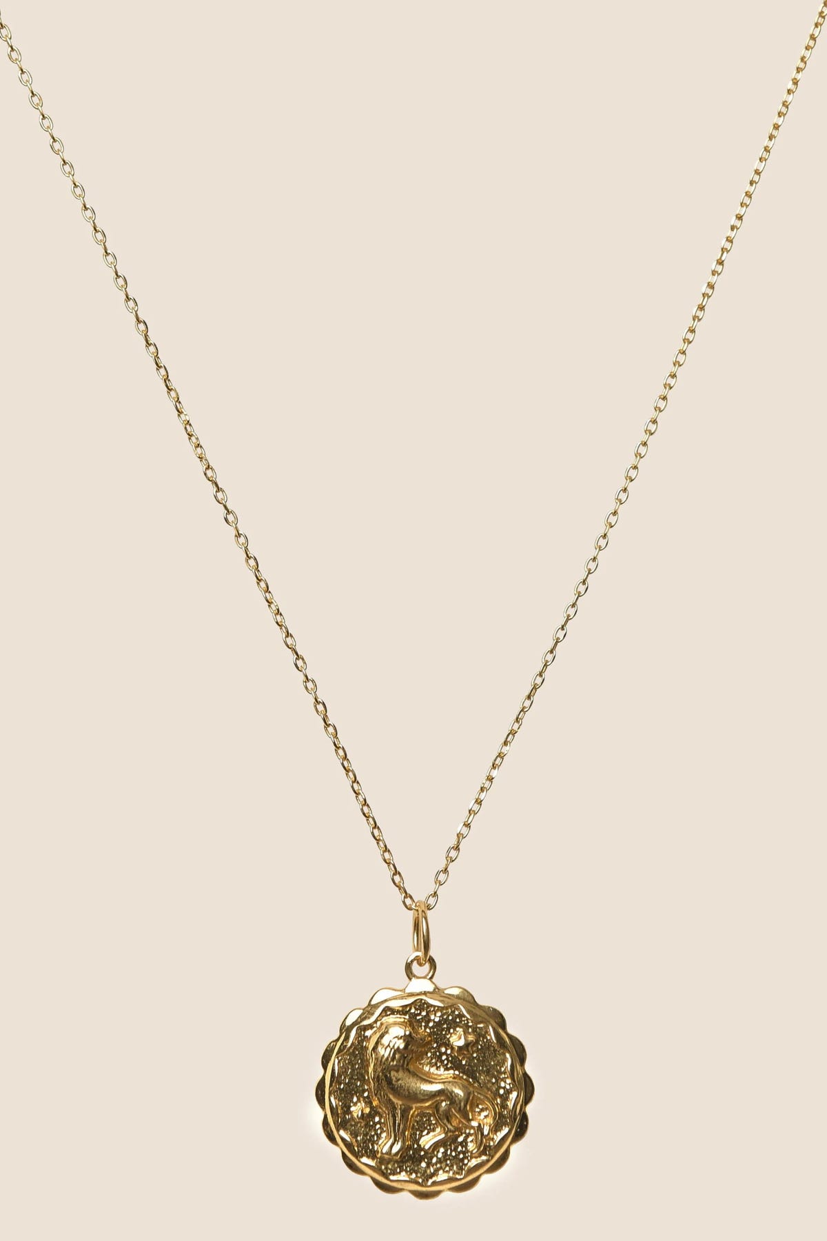 Zodiac - Leo: This gold vermeil necklace features a delicate chain and a round, scalloped pendant embossed with a lion design, presented against a neutral background—a standout addition to any Zodiac jewelry collection.